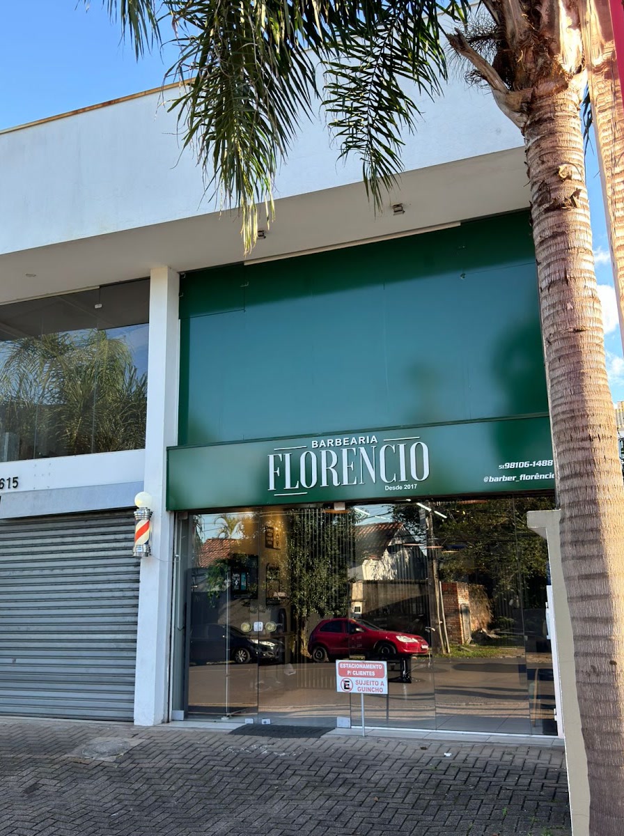 Fachada da Barbearia Florêncio, com o painel verde e o letreiro branco sobre a vitrine