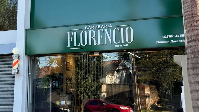 Letreiro da Barbearia Florêncio com o poste de barbeiro na porta, o telefone e o Instagram pintados ao lado